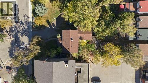 Aerial perspective featuring a shingled roof, mature trees, and an asphalt surface parking area - 14 London Street N, Hamilton, ON 