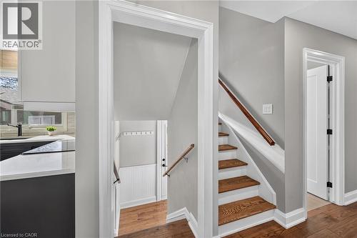Stair case leads down to the access to the backyard and features a little mud-room type corner.  Also, original hardwood stairs leading to the 2nd floor. - 10 Mulock Avenue, Hamilton, ON 