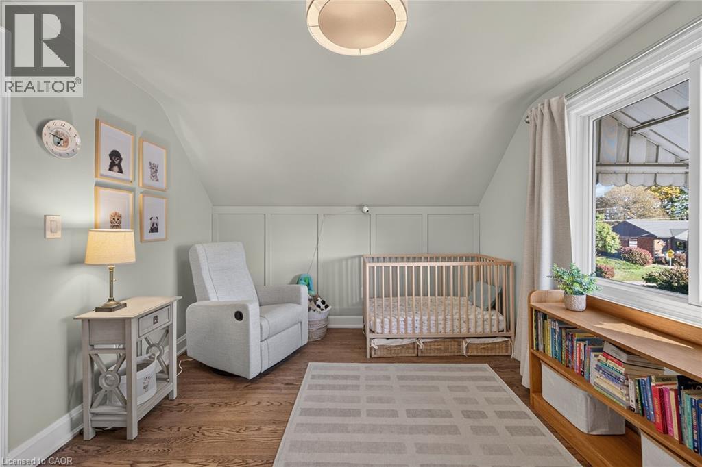 Oak hardwood flooring, panelled wall detailing featured in this cozy bedroom. - 10 Mulock Avenue, Hamilton, ON