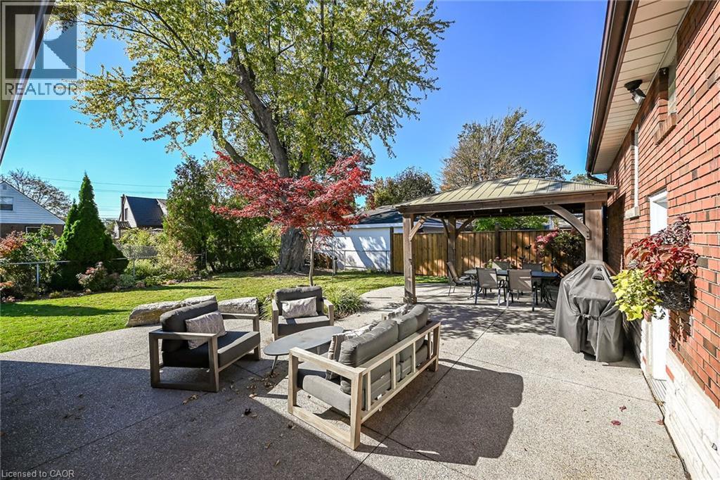 Expansive concrete patio featuring a wooden gazebo, pristine surrounding landscaped grounds with mature trees. - 10 Mulock Avenue, Hamilton, ON