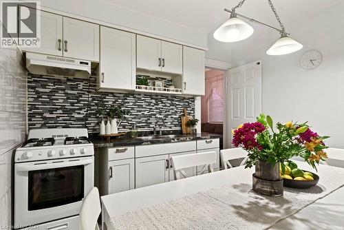 Kitchen featuring white cabinetry, updated backsplash, and gas stove - 66 Beechwood Avenue, Hamilton, ON 
