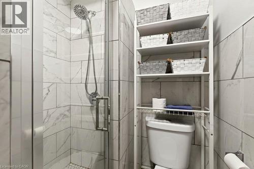Shower enclosure featuring clear glass door, chrome fixtures, and white tiled walls - 66 Beechwood Avenue, Hamilton, ON 