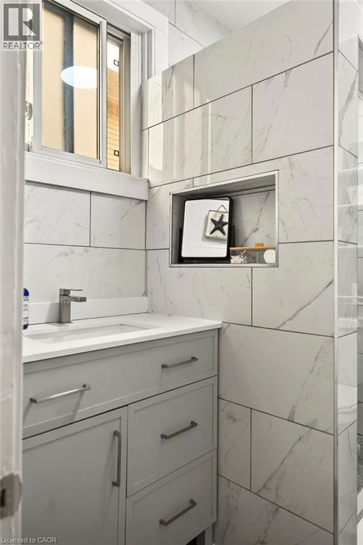Modern bathroom featuring a light gray vanity with brushed nickel hardware, a white countertop, and an undermount sink with a single-handle faucet - 66 Beechwood Avenue, Hamilton, ON