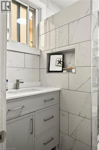 Modern bathroom featuring a light gray vanity with brushed nickel hardware, a white countertop, and an undermount sink with a single-handle faucet - 66 Beechwood Avenue, Hamilton, ON 