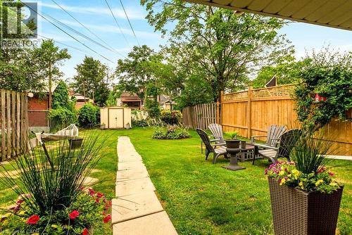 Expansive backyard with lawn, seating area, and a central stone pathway leading to shed - 66 Beechwood Avenue, Hamilton, ON 