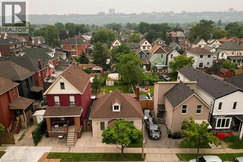 Aerial perspective showcasing a residential neighborhood with diverse housing styles, mature trees, and a distant cityscape - 66 Beechwood Avenue, Hamilton, ON 
