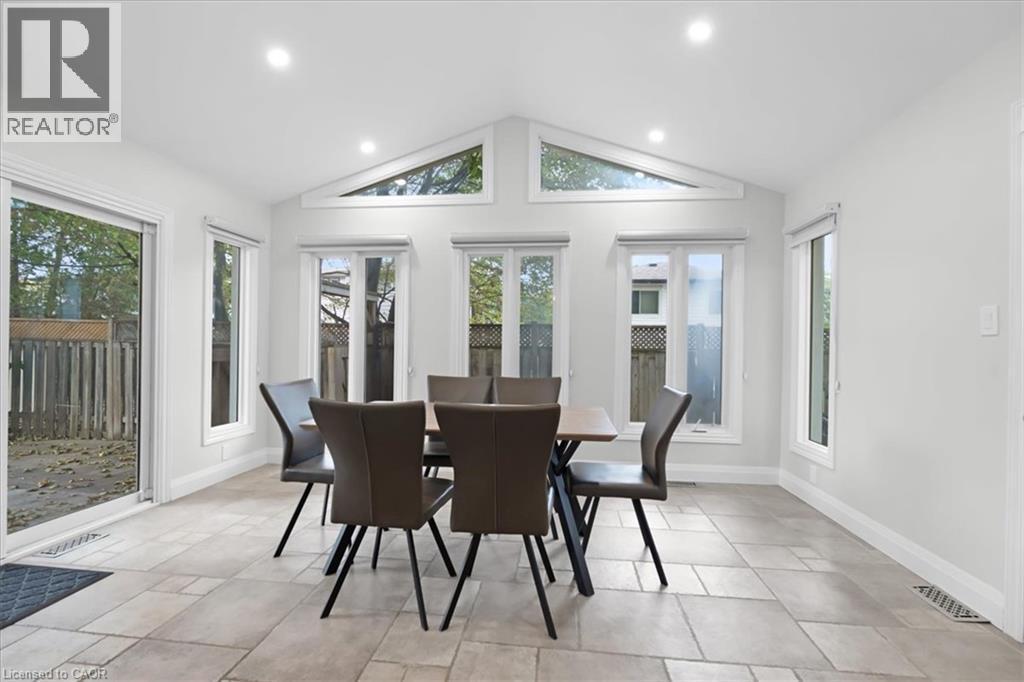 Sliding glass door access to the outdoor area, vaulted ceiling with recessed lighting, multiple windows, and light-toned tile flooring - 31 Berrisfield Crescent, Hamilton, ON