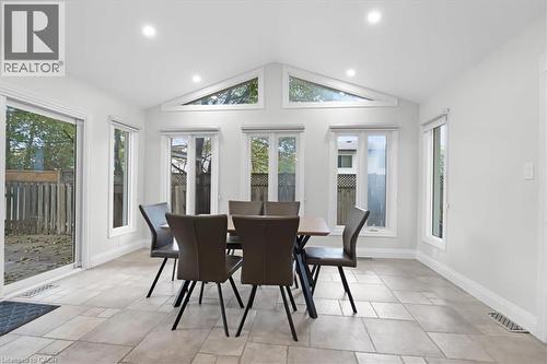 Sliding glass door access to the outdoor area, vaulted ceiling with recessed lighting, multiple windows, and light-toned tile flooring - 31 Berrisfield Crescent, Hamilton, ON 
