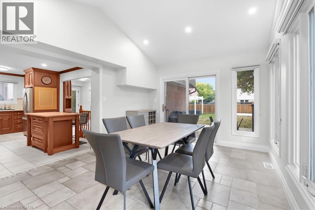 Open-concept dining and kitchen area featuring a light-filled space with recessed ceiling lighting, tile flooring, and glass sliding doors opening to the backyard - 31 Berrisfield Crescent, Hamilton, ON
