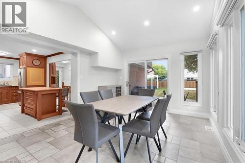 Open-concept dining and kitchen area featuring a light-filled space with recessed ceiling lighting, tile flooring, and glass sliding doors opening to the backyard - 31 Berrisfield Crescent, Hamilton, ON 