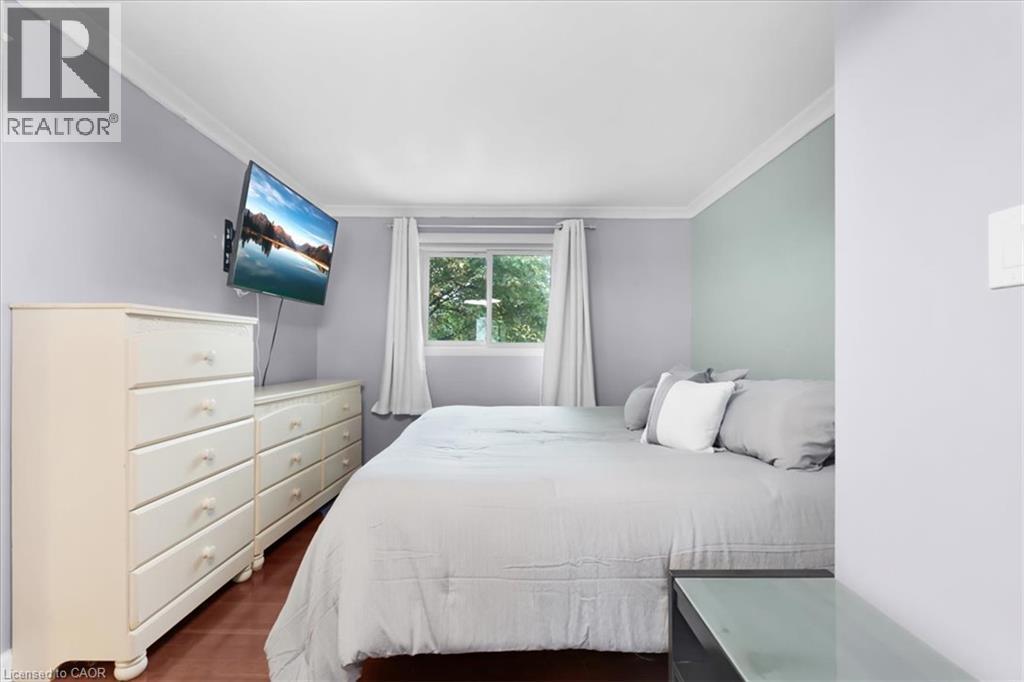 Window with white curtains, wood-finish flooring, and crown molding - 31 Berrisfield Crescent, Hamilton, ON