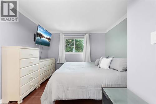 Window with white curtains, wood-finish flooring, and crown molding - 31 Berrisfield Crescent, Hamilton, ON 