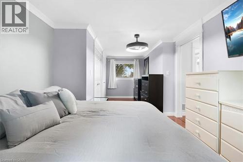 Hardwood-finish flooring, crown molding, white trim, sliding closet doors, and a ceiling-mounted light fixture - 31 Berrisfield Crescent, Hamilton, ON 