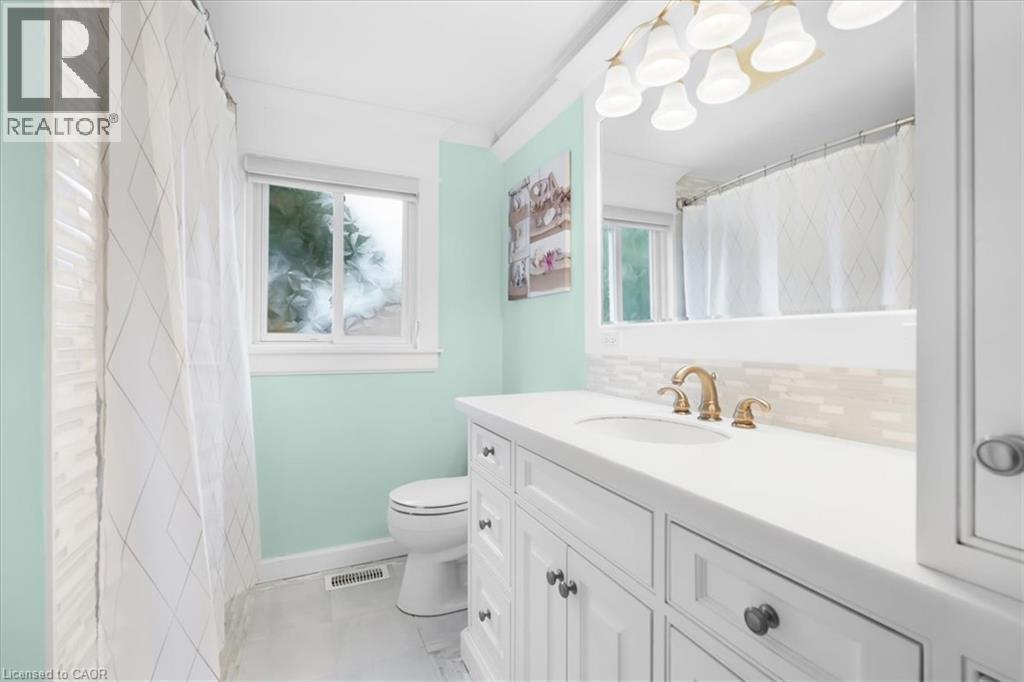 White shaker vanity with a light countertop, gold-finish faucet, and tiled backsplash - 31 Berrisfield Crescent, Hamilton, ON