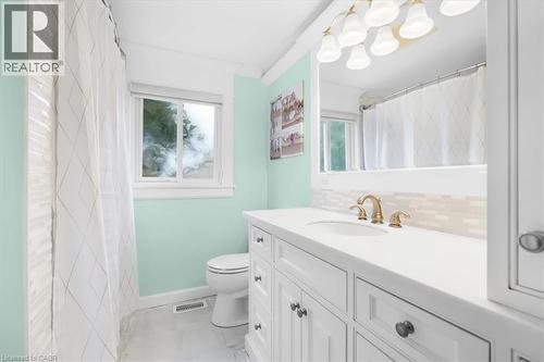 White shaker vanity with a light countertop, gold-finish faucet, and tiled backsplash - 31 Berrisfield Crescent, Hamilton, ON 