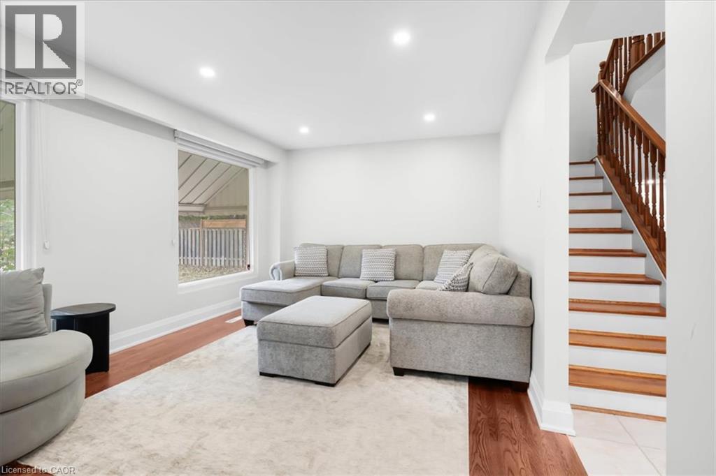 Recessed lighting, wood-finish flooring, white walls, large windows, and a hardwood staircase with white risers - 31 Berrisfield Crescent, Hamilton, ON