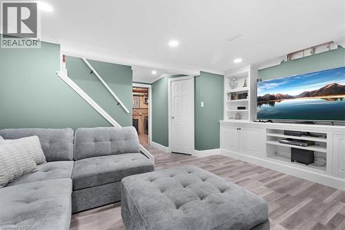 Recessed lighting, wood-finish flooring, white built-in entertainment center, built-in shelving, and white interior doors - 31 Berrisfield Crescent, Hamilton, ON 