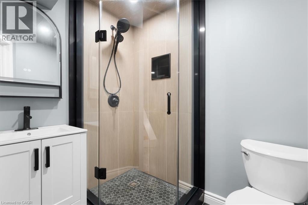 Glass-enclosed shower with matte black fixtures, hexagonal tile flooring, and a built-in shower niche - 31 Berrisfield Crescent, Hamilton, ON