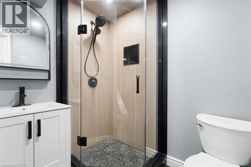 Glass-enclosed shower with matte black fixtures, hexagonal tile flooring, and a built-in shower niche - 31 Berrisfield Crescent, Hamilton, ON 