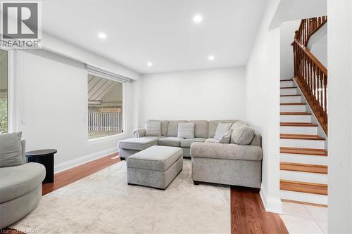 Recessed lighting, wood-finish flooring, white walls, large windows, and a hardwood staircase with white risers - 31 Berrisfield Crescent, Hamilton, ON 