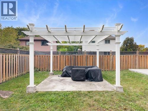 White pergola over a concrete patio with wood fencing - 31 Berrisfield Crescent, Hamilton, ON 