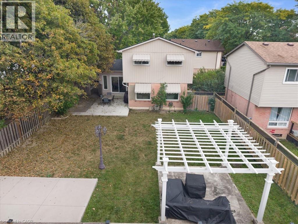 Expansive backyard featuring a pergola, concrete patio, and mature perimeter trees - 31 Berrisfield Crescent, Hamilton, ON