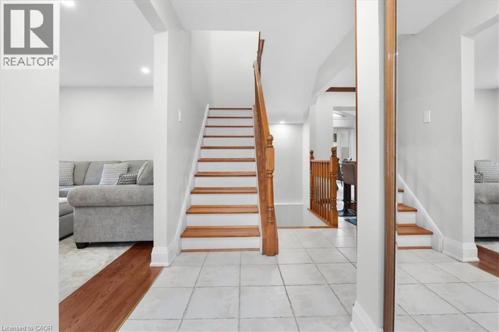 Hardwood stairs with white risers, light tile flooring, wood-finish flooring, and recessed lighting - 31 Berrisfield Crescent, Hamilton, ON