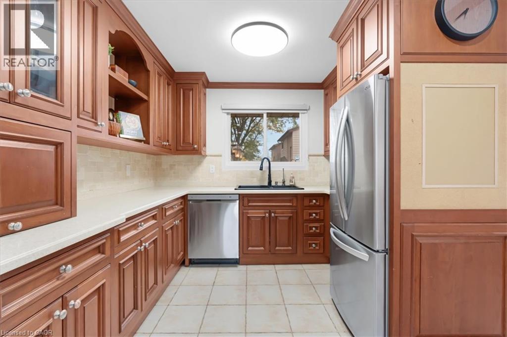 Wood-finish cabinetry with display shelving, stainless steel appliances, light-toned countertop, tiled backsplash, and recessed lighting - 31 Berrisfield Crescent, Hamilton, ON