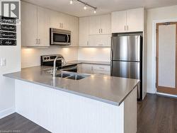 Kitchen featuring light-toned cabinetry, solid surface countertops, stainless steel appliances, under-cabinet lighting, and track lighting - 