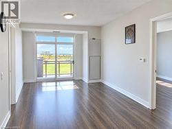 Wood-finish flooring, neutral wall tones, flush-mount lighting, and glass sliding doors leading to an exterior balcony - 