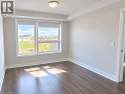 Room featuring wood-finish flooring, neutral wall paint, a double-pane window, and a ceiling-mounted light fixture - 