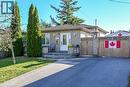 Single-story exterior featuring masonry siding, a concrete front porch with ornamental balusters, asphalt driveway, and a wood privacy fence - 411 Queen Victoria Drive, Hamilton, ON 