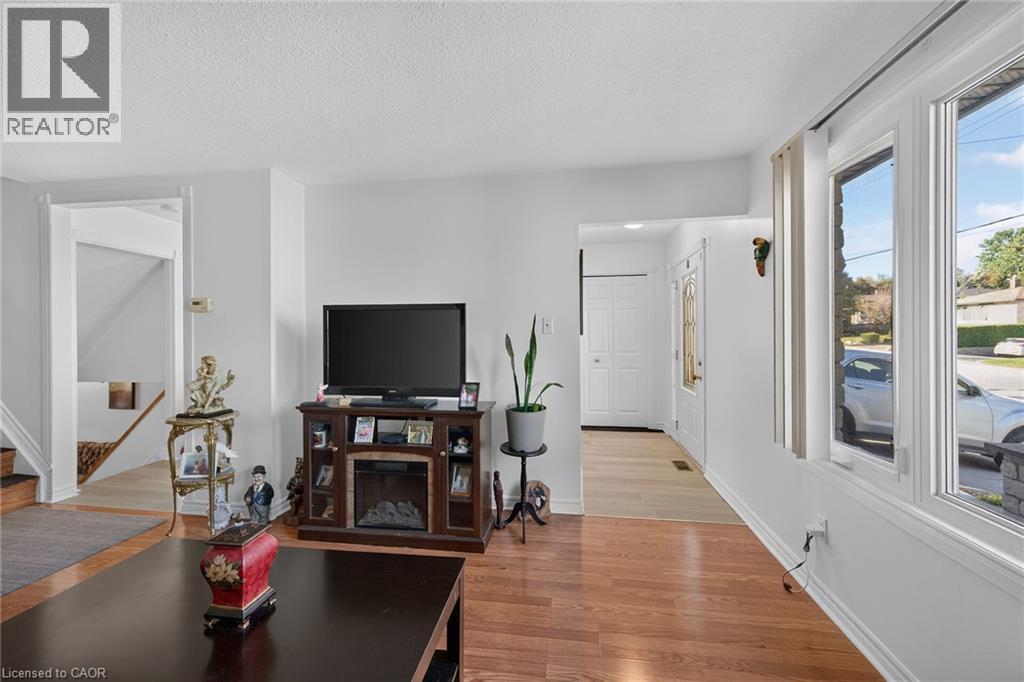 Living area featuring wood-finish flooring, a large bay window, and a paneled entry door with glass inserts - 411 Queen Victoria Drive, Hamilton, ON
