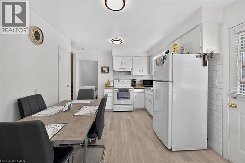 Kitchen featuring white shaker-style cabinetry, wood-finish flooring, white subway tile backsplash, and flush-mount ceiling lighting - 411 Queen Victoria Drive, Hamilton, ON 