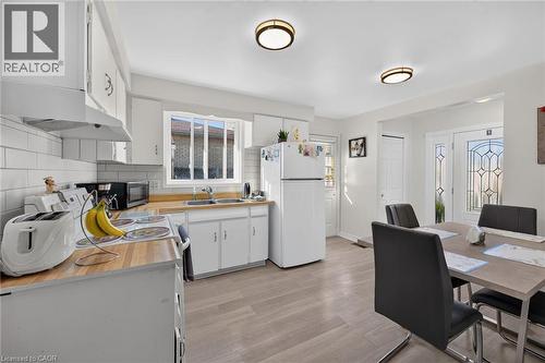 Kitchen featuring wood-finish countertops, white cabinetry, light-toned wood-finish flooring, subway tile backsplash, and flush-mount lighting fixtures - 411 Queen Victoria Drive, Hamilton, ON 