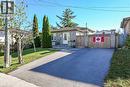 Single-story masonry exterior featuring a private asphalt driveway, integrated wood-panel fencing with stone pillars, and mature landscaping - 411 Queen Victoria Drive, Hamilton, ON 