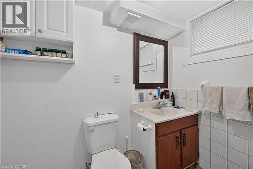 Bathroom featuring white cabinetry, integrated sink, wooden vanity base, framed mirror, and white wall-tiled surround - 411 Queen Victoria Drive, Hamilton, ON 