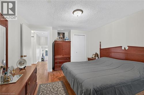 Bedroom featuring wood-finish flooring, a flush-mount light fixture, and a reach-in closet with white doors - 411 Queen Victoria Drive, Hamilton, ON 