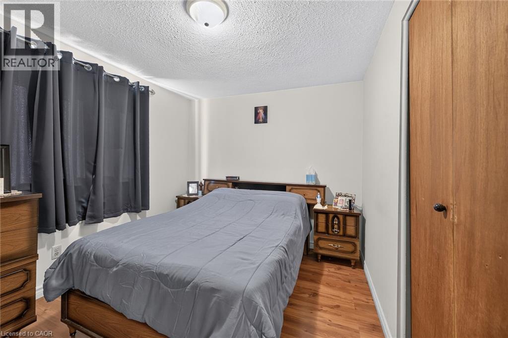 Wood-finish flooring, textured ceiling, flush-mount ceiling light fixture, and wooden closet door - 411 Queen Victoria Drive, Hamilton, ON