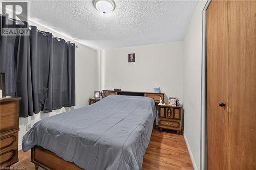 Wood-finish flooring, textured ceiling, flush-mount ceiling light fixture, and wooden closet door - 411 Queen Victoria Drive, Hamilton, ON 