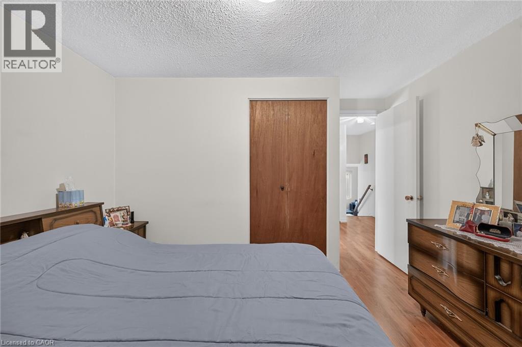 Room featuring wood-finish flooring, a wood-veneer closet door, and a textured ceiling - 411 Queen Victoria Drive, Hamilton, ON