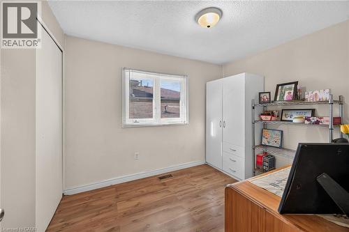 Neutral-toned interior room featuring wood-finish flooring, a single double-panel window, a sliding-door closet, and a flush-mount ceiling light fixture - 411 Queen Victoria Drive, Hamilton, ON 