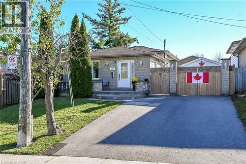 Single-story masonry exterior featuring a covered front porch, asphalt driveway, and private gated side access - 411 Queen Victoria Drive, Hamilton, ON 