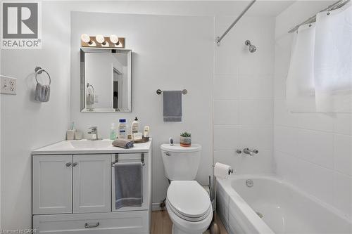 Bathroom featuring a white vanity with an integrated sink, polished chrome faucet, framed mirror, three-light fixture, and a tiled tub-shower combination - 411 Queen Victoria Drive, Hamilton, ON 