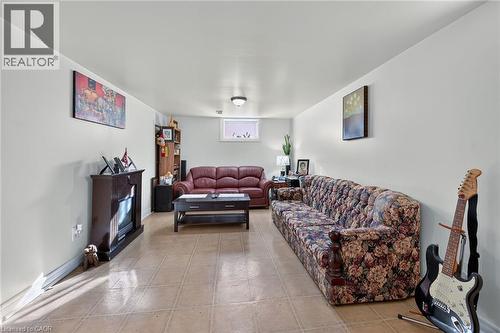 Interior space featuring tile flooring, neutral wall paint, a flush-mount ceiling light fixture, a small hopper-style window, and a built-in electric fireplace insert with a dark wood-finish mantel - 411 Queen Victoria Drive, Hamilton, ON 