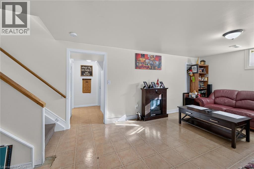 Open interior space featuring light-toned tile flooring, an electric fireplace with a dark wood-finish mantel, and a staircase with a wooden handrail - 411 Queen Victoria Drive, Hamilton, ON