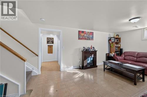 Open interior space featuring light-toned tile flooring, an electric fireplace with a dark wood-finish mantel, and a staircase with a wooden handrail - 411 Queen Victoria Drive, Hamilton, ON 