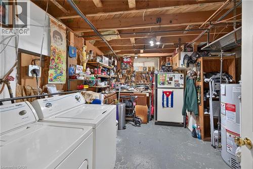 Utility space featuring exposed beam ceiling, painted concrete flooring, integrated laundry hookups, and built-in workbench cabinetry - 411 Queen Victoria Drive, Hamilton, ON 
