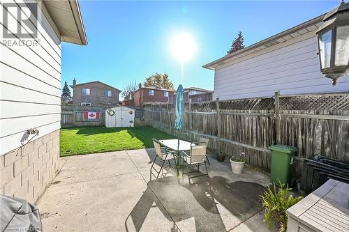 Fenced backyard featuring a concrete patio, green lawn, and storage shed - 411 Queen Victoria Drive, Hamilton, ON 