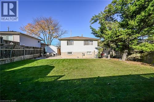 Spacious backyard featuring a manicured lawn, concrete patio, perimeter wood fencing, and mature trees - 411 Queen Victoria Drive, Hamilton, ON 